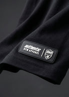 RTLS raised rubber badge, close-up of the hem patch detail on a black garment